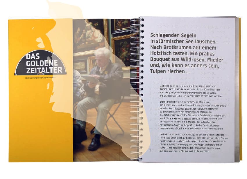 Das Bild zeigt ein aufgeschlagenes Lese-Tast-Hörbuch. In dem Hörbuch steht viel Text. Links sieht man auch ein Foto von einer Person. Das Hörbuch gibt barriere-freie Informationen zu einem Thema.